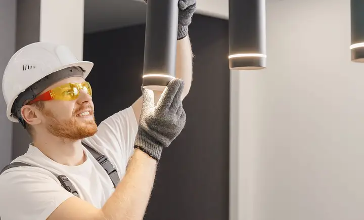 A worker fitting an exterior light on the side of a house